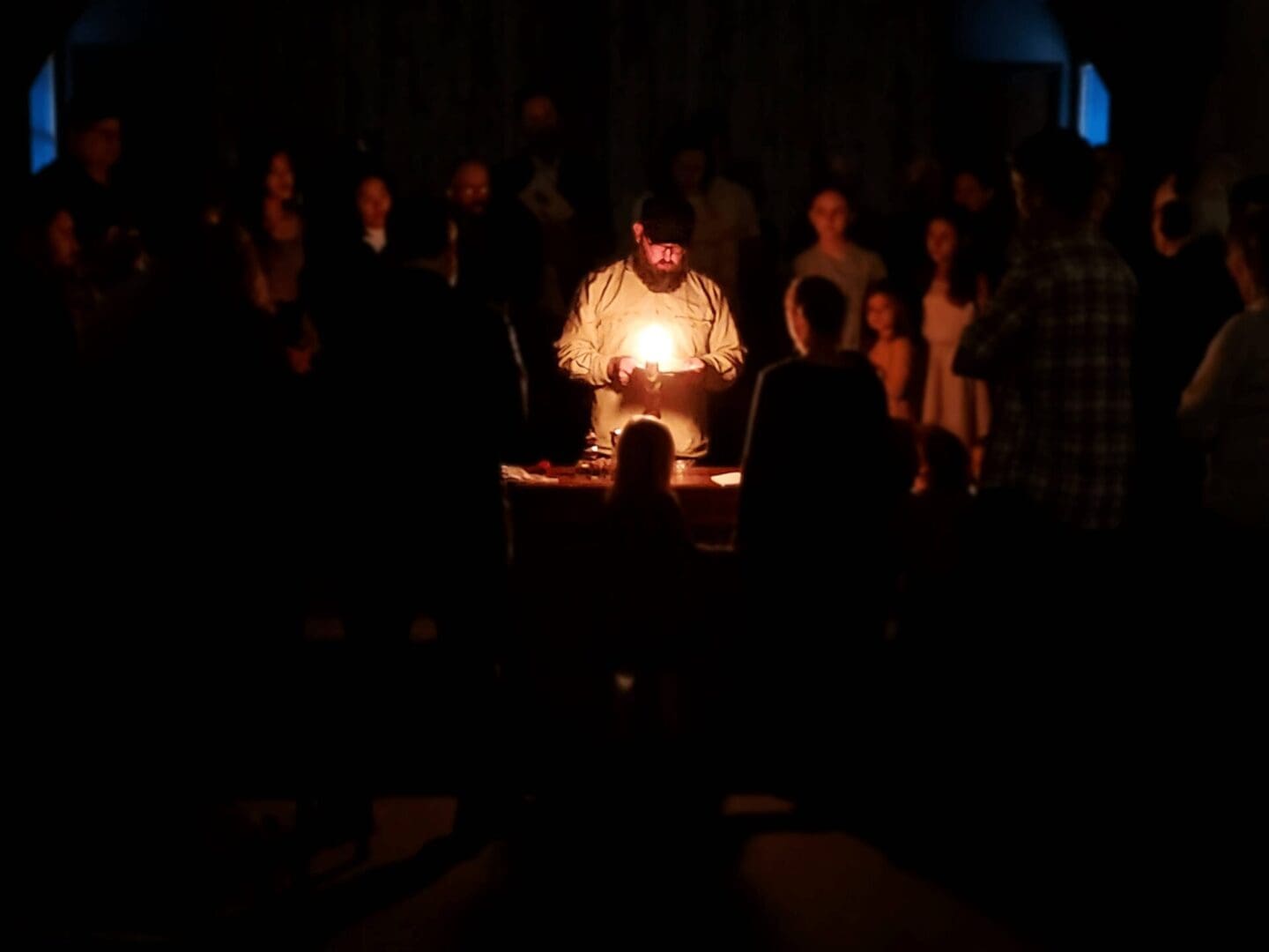A man is lighting candles in the dark.